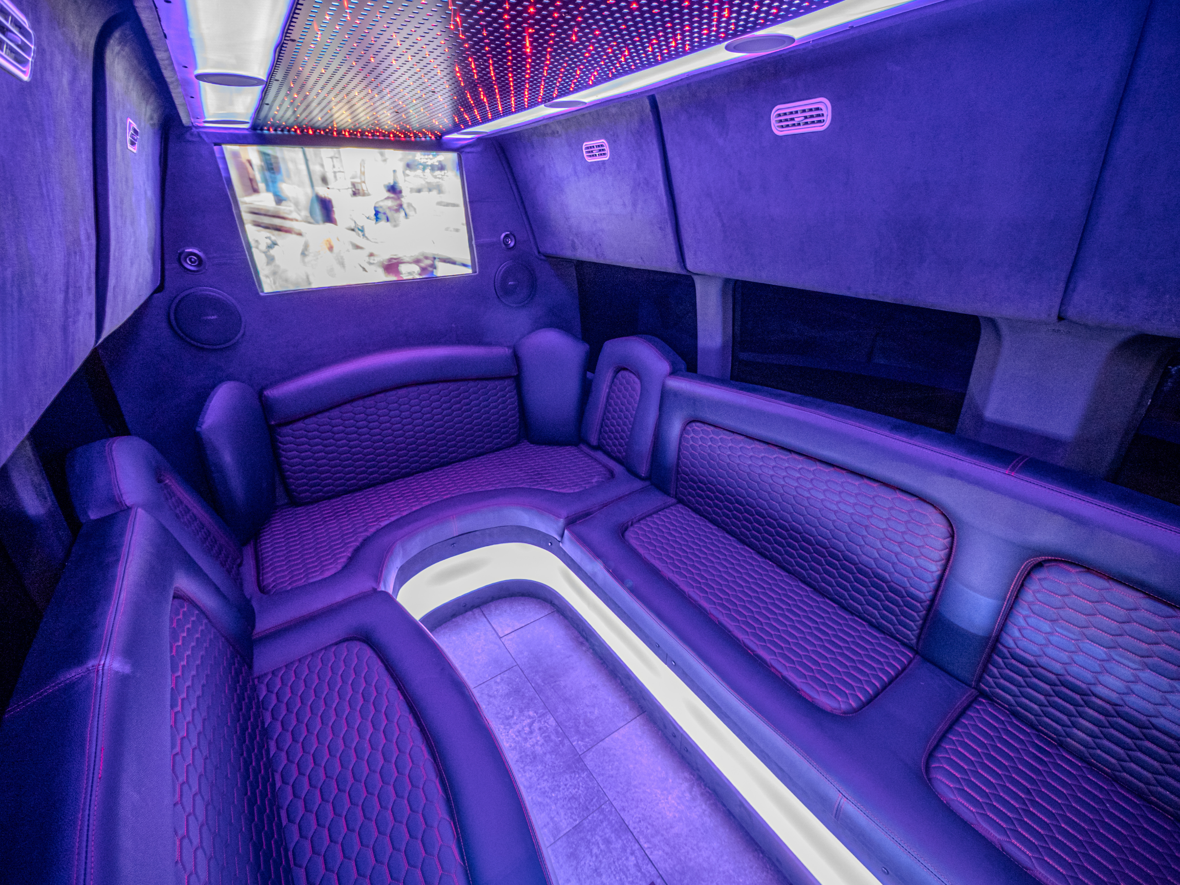 Van Limo party bus interior in Puerto Rico featuring LED lighting, wrap-around leather seats, and TV screen