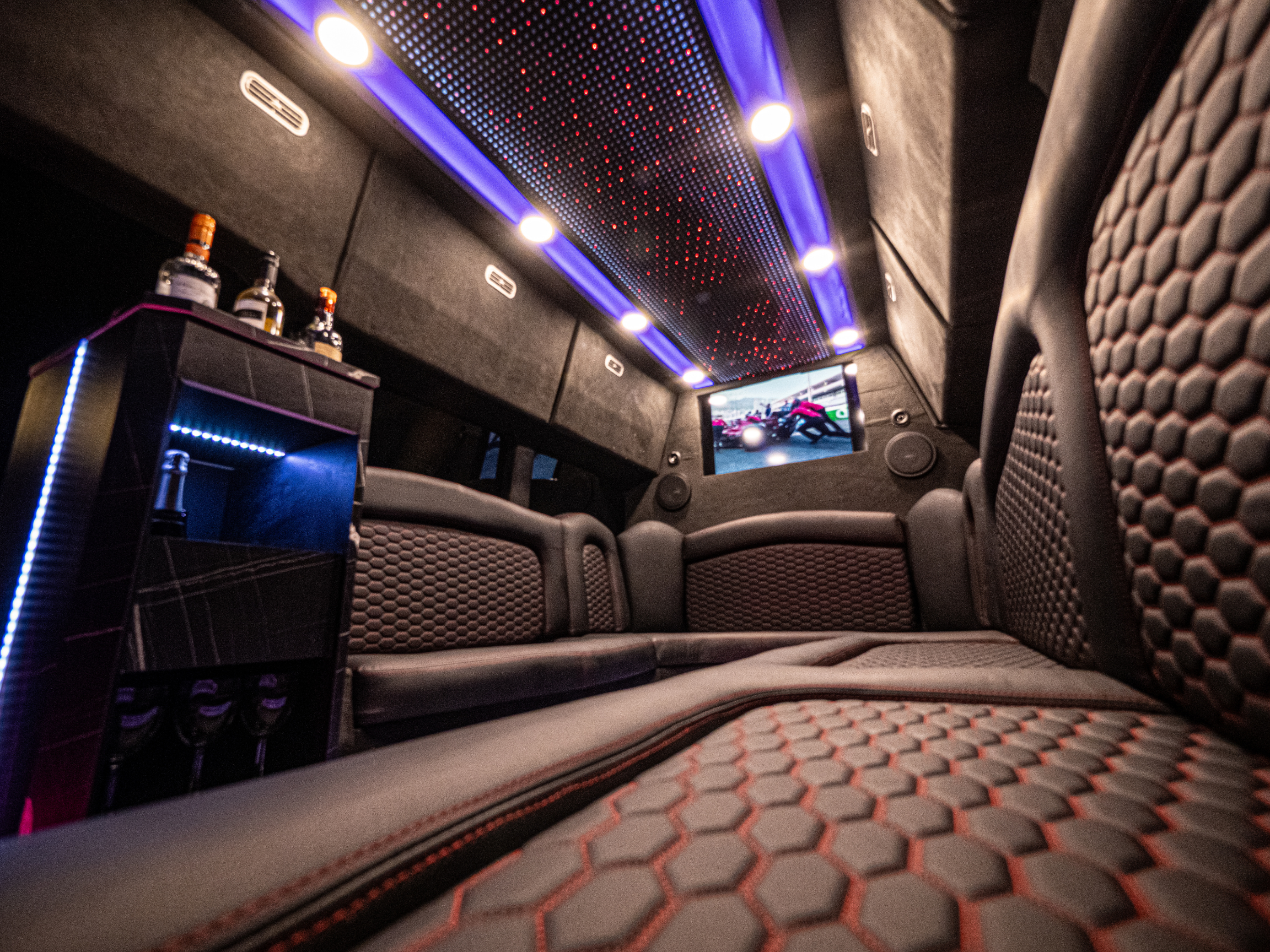 Close-up of Van Limo party bus interior in Puerto Rico with leather seats, minibar, TV screen, and LED ceiling lights