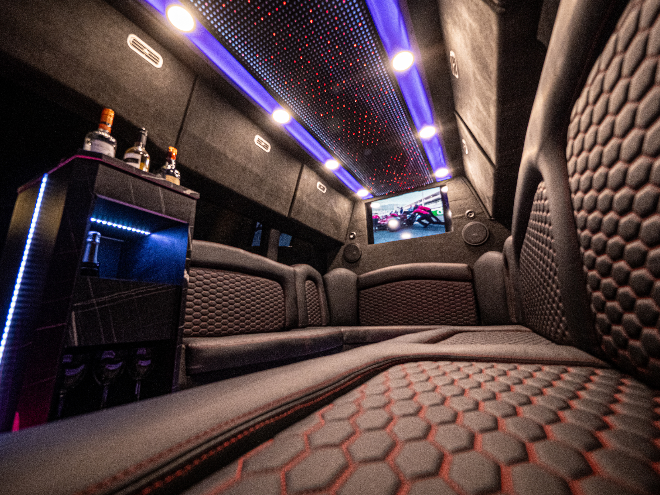 Van Limo party bus interior in Puerto Rico with bar, TV screen, LED lights, and leather seating