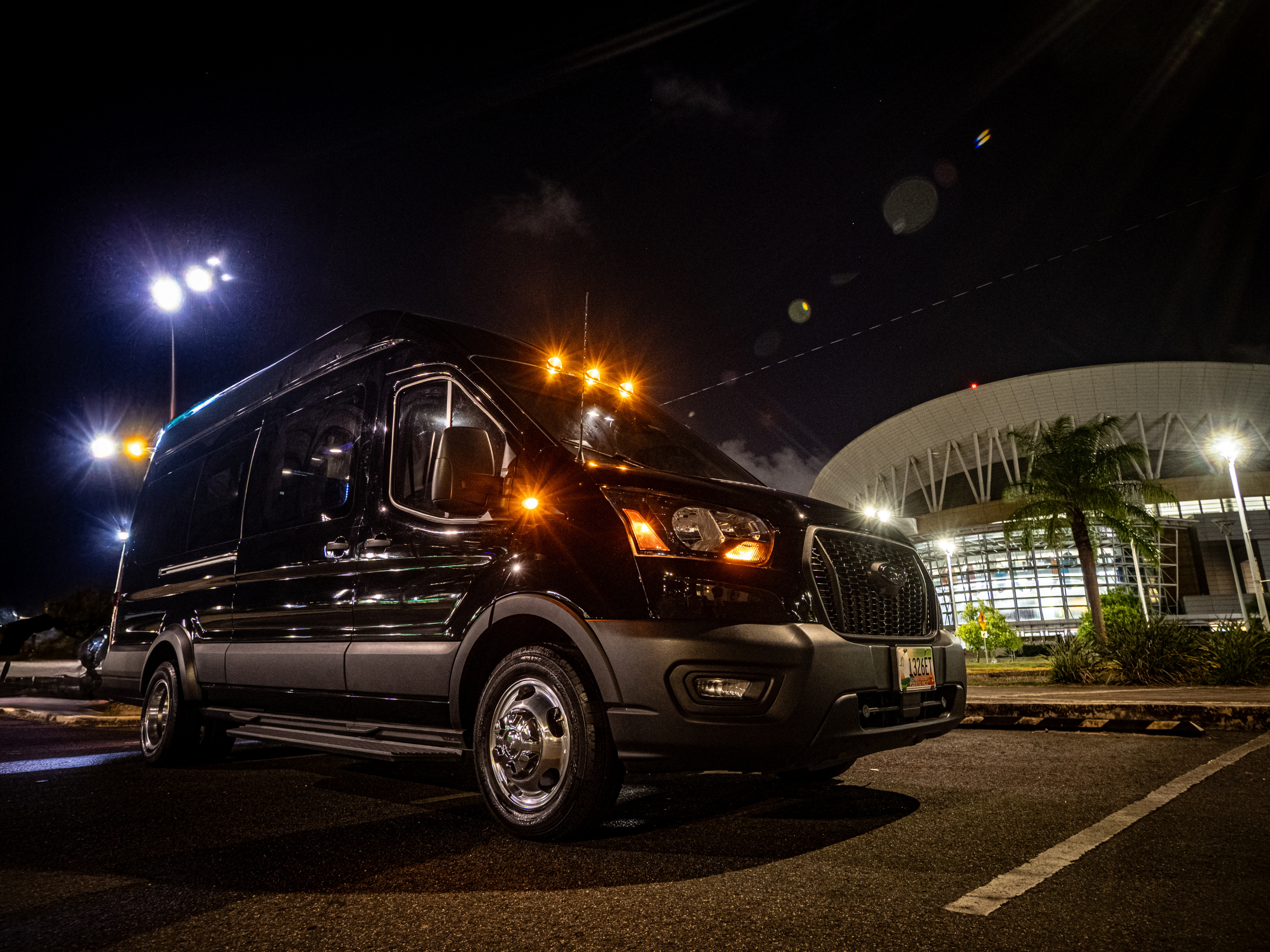 Luxury Van Limo parked at night in Puerto Rico in front of Coliseo José Miguel Agrelot, with LED lights and black finish