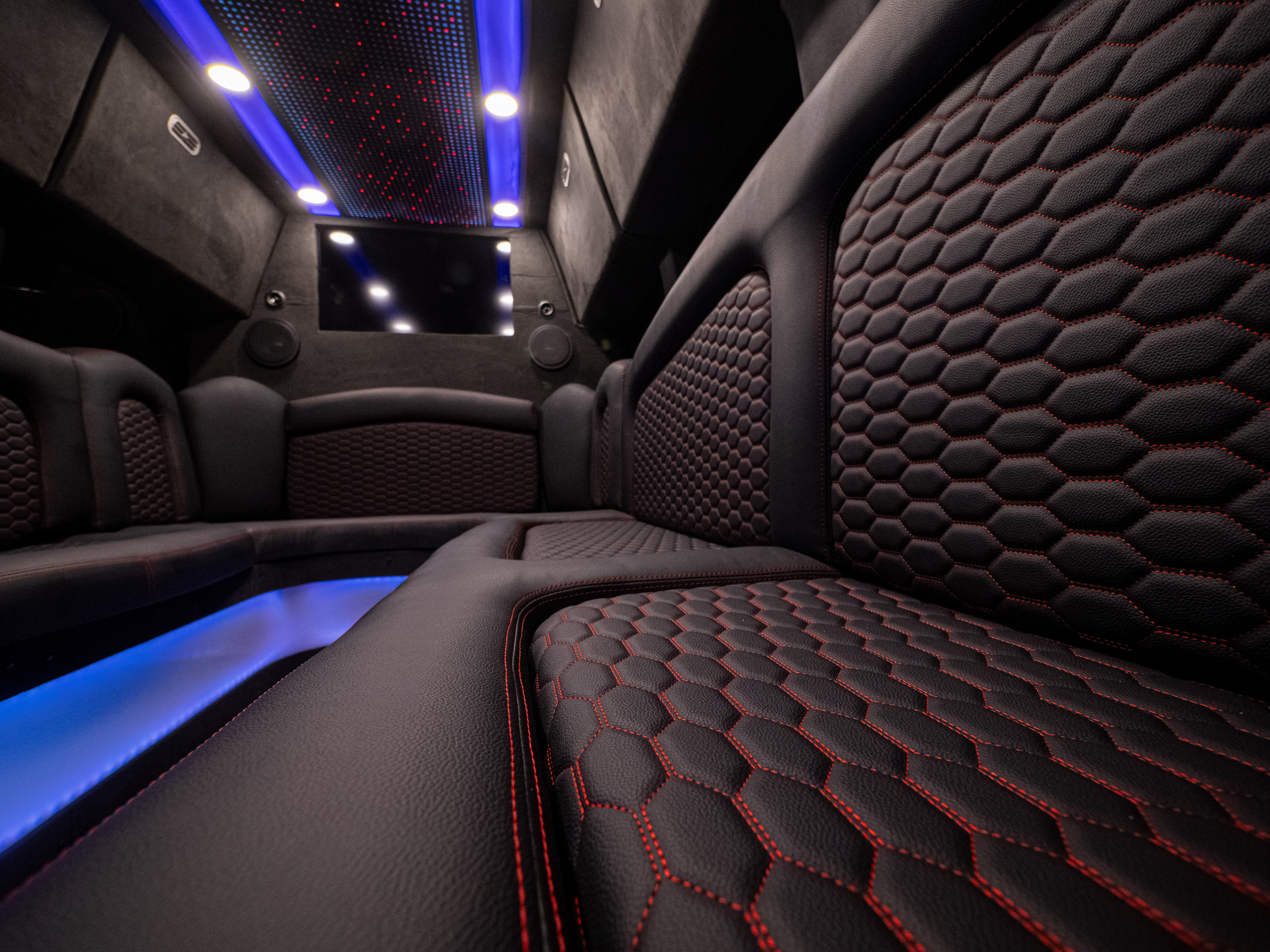 Detailed close-up of Van Limo leather seats with red stitching and ambient LED lighting in Puerto Rico party bus