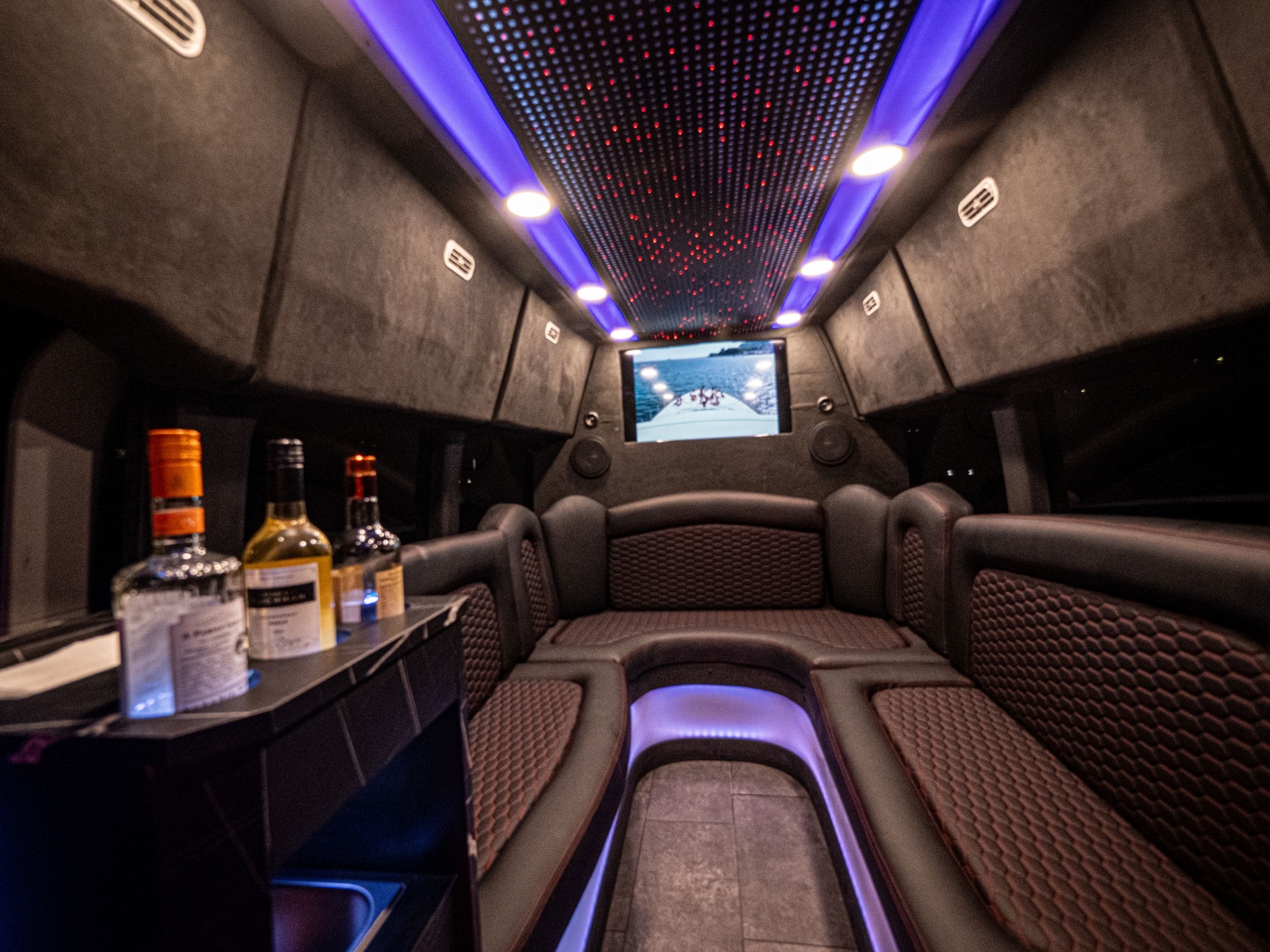 Interior of Van Limo party bus in Puerto Rico with bar, TV screen, leather seats, and LED ceiling lights